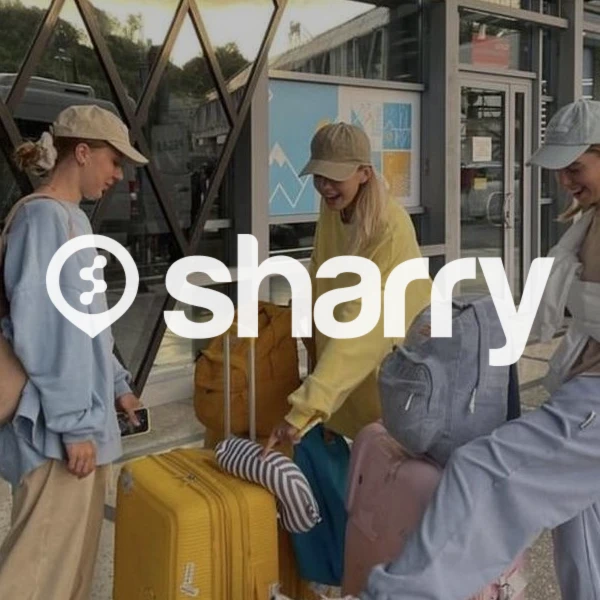 логотип і назва компанії Sharry на фоні трьох дівчат у кепках та спортивному одязі, що стоять з валізами біля входу до вокзалу